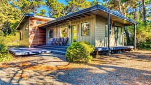 A two-story cabin with a porch, surrounded by trees. - Stunning new home with furnished deck & easy beach access (Florence)