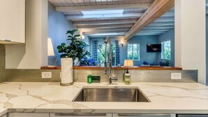 A kitchen with a large sink, countertop, and wooden ceiling beams. - Stunning new home with furnished deck & easy beach access (Florence)