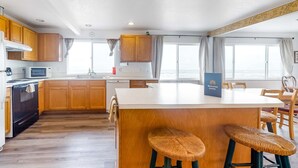 Ett modernt kök med träskåp, en köksö med barstolar och en välkomnande skylt med texten ”Välkommen hem”.