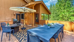 An outdoor deck with a table and chairs, a grill, and a large umbrella. - Dog-friendly home with grill, deck, firepit, balcony, & mountain view (Black Butte Ranch)