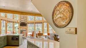 Una cocina con una isla grande, chimenea de piedra y comedor con mobiliario para exteriores.