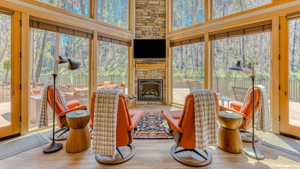 Una habitación con chimenea, ventanas amplias y dos mecedoras.