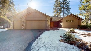 A two-story house with a garage, a front porch, and a snow-covered driveway. - Spacious home with fireplace, private hot tub, AC, & SHARC passes (Sunriver)