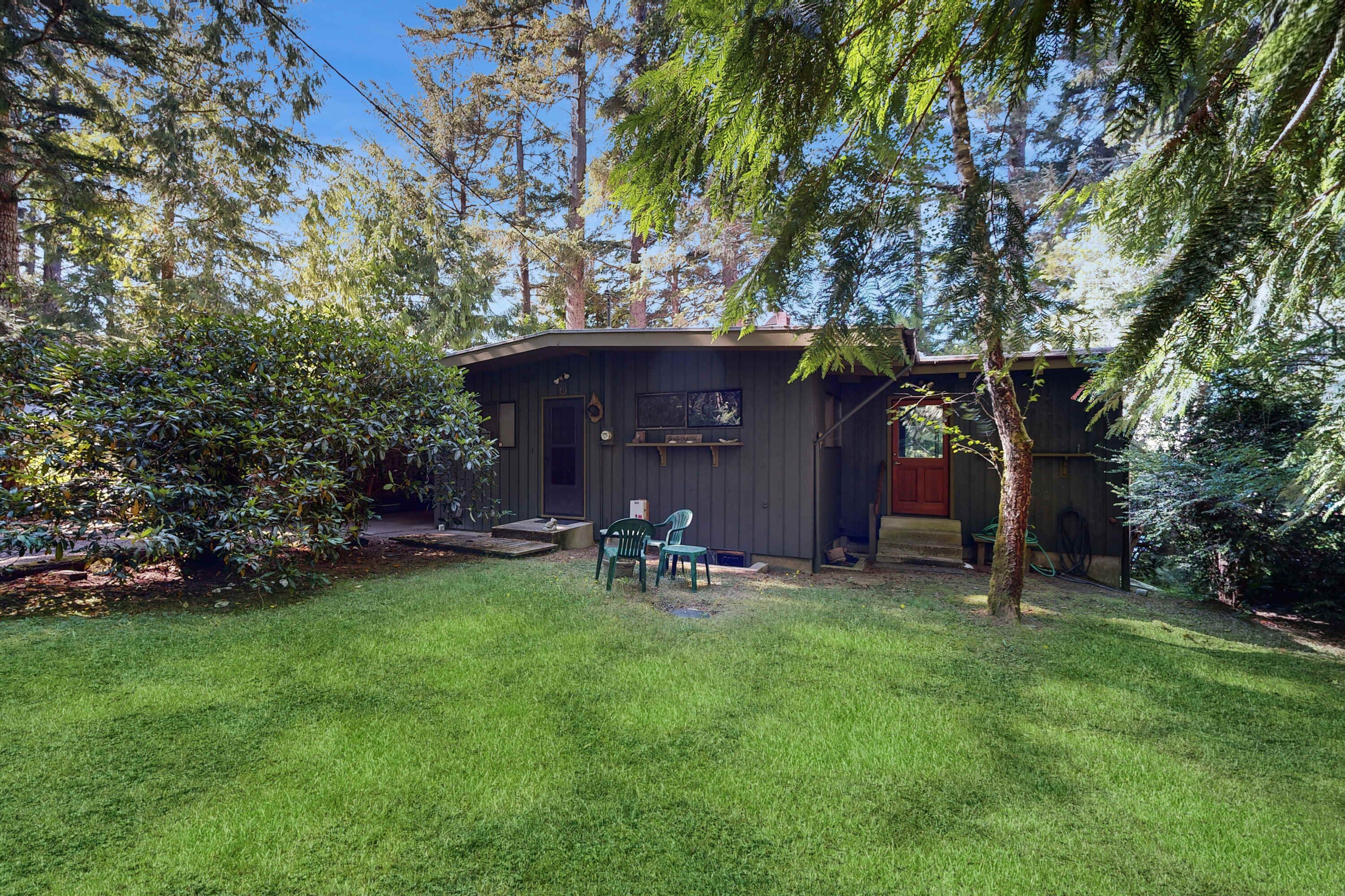 A house with a small deck, a TV mounted on the wall, and a lawn.