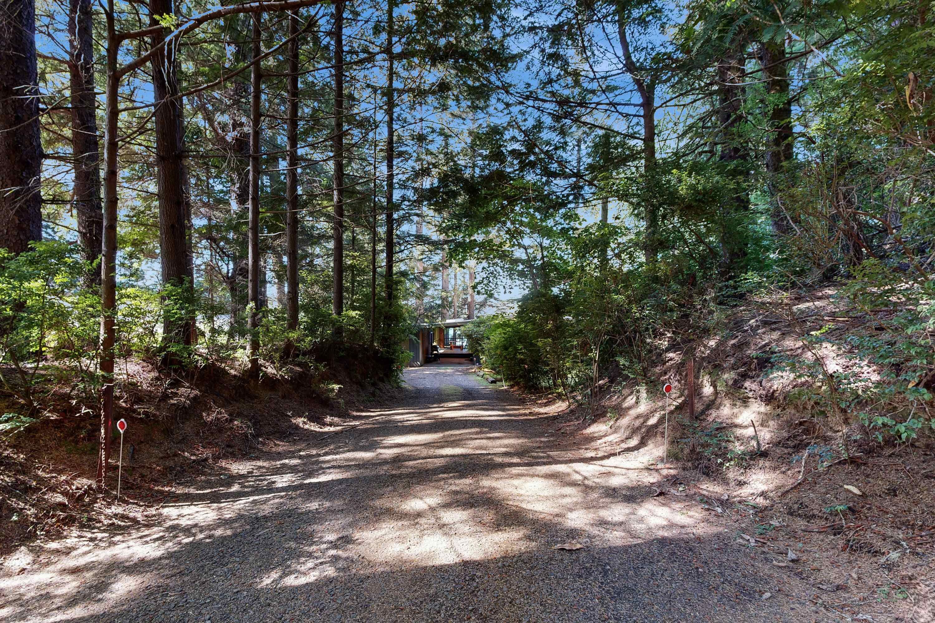 Un sentier bordé d’arbres mène à un bâtiment sur lequel on peut voir une enseigne rouge.