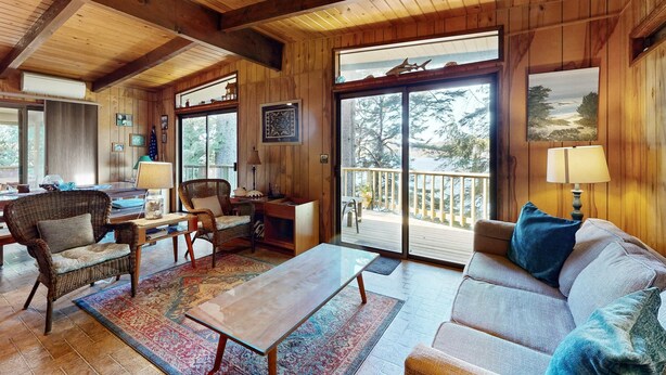 A wooden interior with a sofa, chairs, a table, and a view through a large window. - Unique lakefront cabin near the dunes with a private dock & fireplace (Florence)