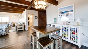 Un comedor con una mesa y sillas de madera, un armario blanco con puertas de vidrio y una araña.