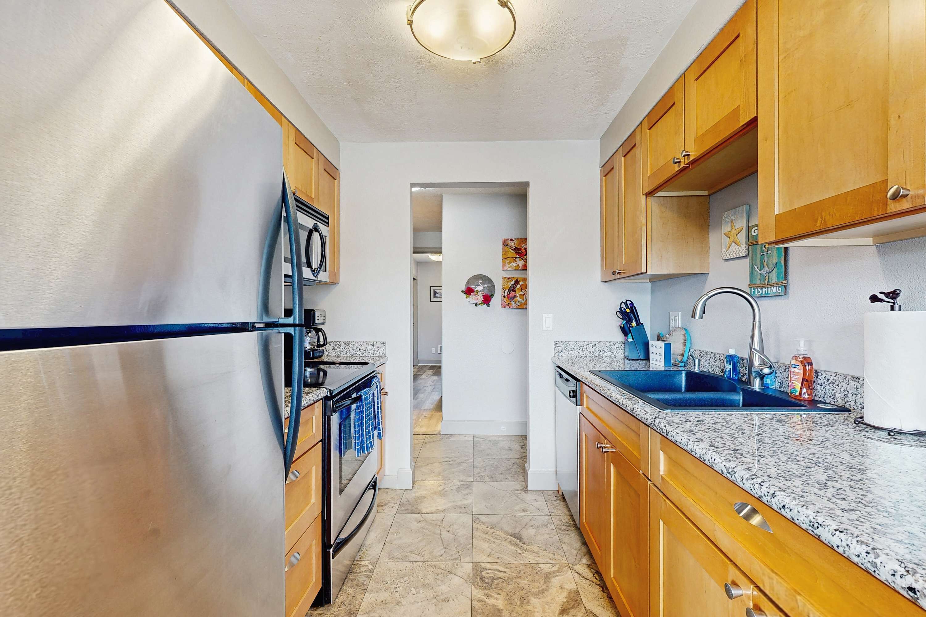 A kitchen with wooden cabinets, a stainless steel refrigerator, a sink, and a dishwasher.