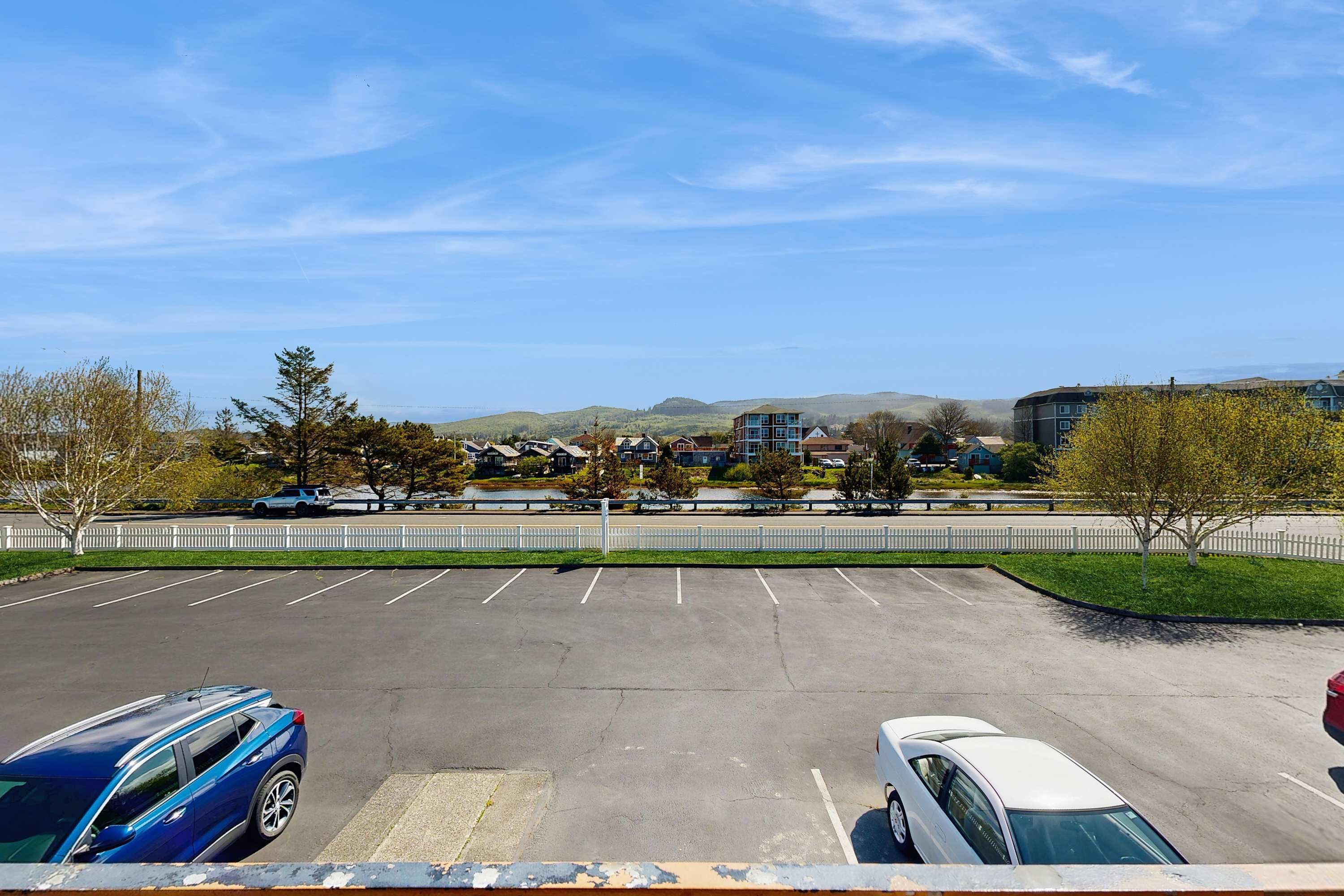 Ein Parkplatz mit zwei Autos, einem weißen Zaun und Gebäuden im Hintergrund.