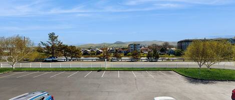 A parking lot with two cars, a white fence, and buildings in the background.