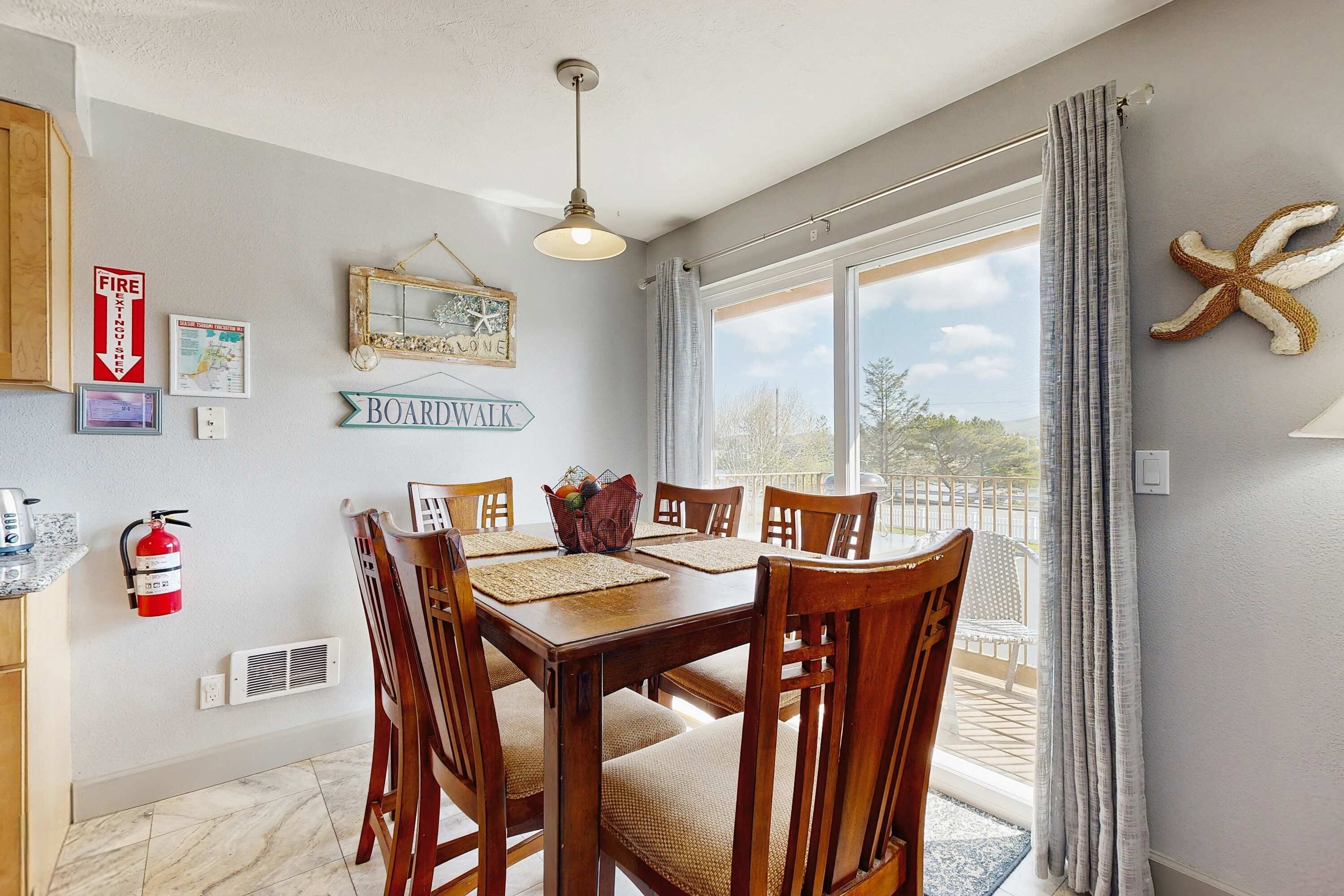 A dining area with a wooden table, chairs, a fire extinguisher, a ceiling light, and a view of the outdoors.