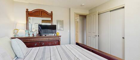 A bedroom with a bed, dresser, television, and a door.