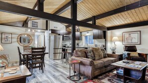 A spacious living area with a wooden ceiling, a leather sofa, a coffee table, and a dining table with chairs. - Remodeled home with hot tub, SHARC passes, & close to Sunriver Village - dogs OK (Sunriver)