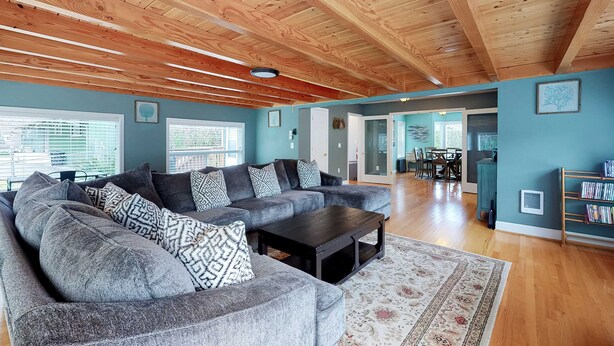 A spacious living room with a large sectional sofa, a dark coffee table, and a wooden ceiling. - Coastal beach retreat with deck, grill, fireplace, washer&dryer, and free WiFi (Seaside)