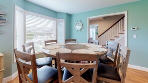 A dining area with a round table, wooden chairs, and a wall clock. - Coastal beach retreat with deck, grill, fireplace, washer&dryer, and free WiFi (Seaside)