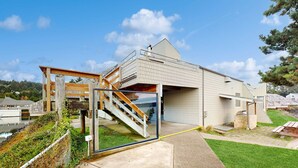 Ein modernes Haus mit Glastür, einer Holztreppe und einer kleinen Außenbereiches mit Grill.