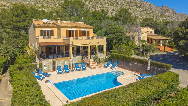 Une villa à deux étages dotée d’une piscine, de chaises longues et offrant une vue sur les montagnes.