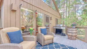 A covered deck with wicker furniture, a grill, and a potted plant. - Home near Deschutes River, WiFi, & private hot tub - dogs ok (Sunriver)