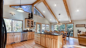 A spacious kitchen with wooden cabinets, a central island, and large windows. - Home near Deschutes River, WiFi, & private hot tub - dogs ok (Sunriver)