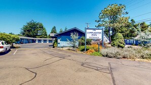 A motel with a blue exterior, a sign indicating the entrance, and a parking lot. - Cute beach room with fast WiFI - walk to downtown shops & eats (Bandon)