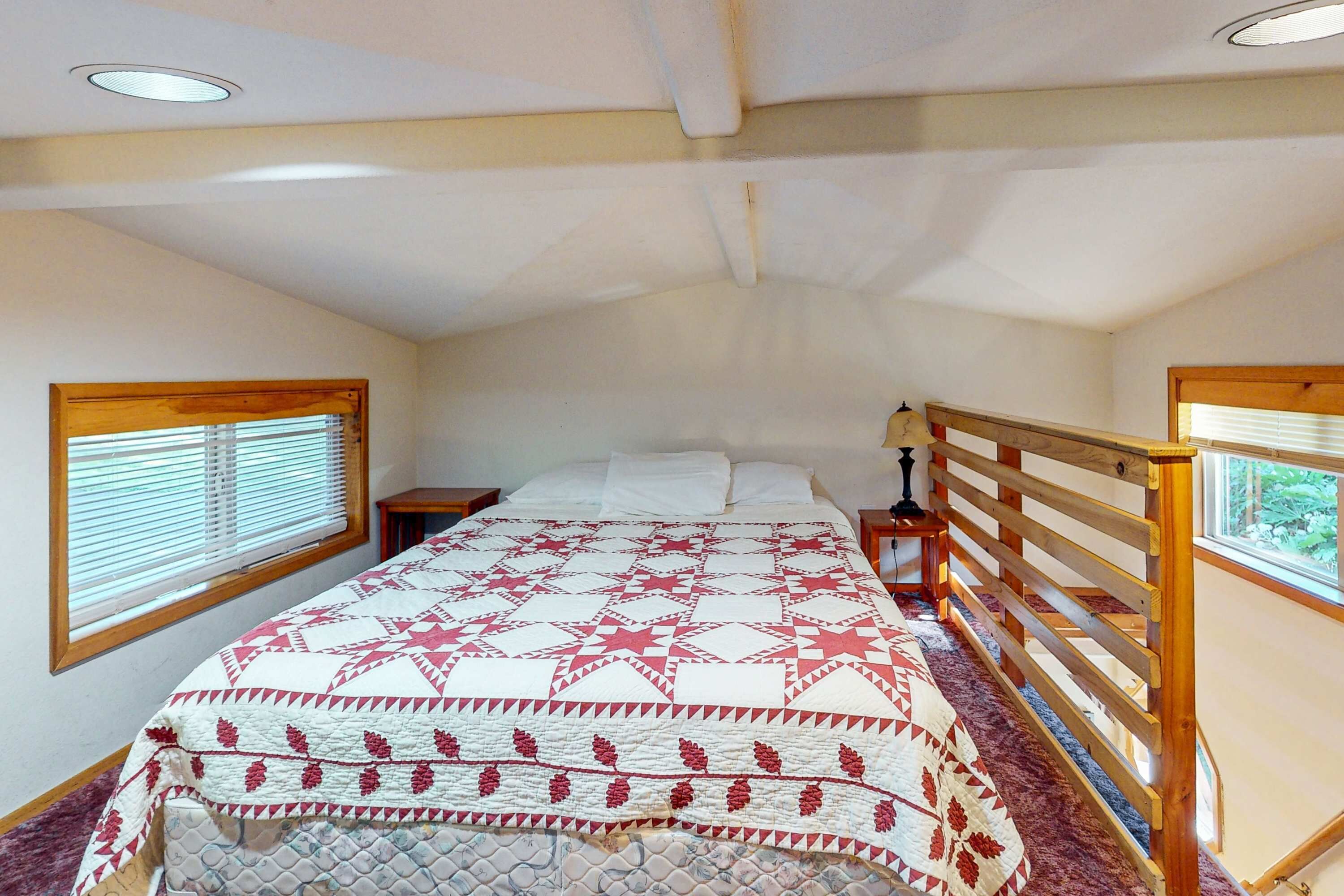 Een slaapkamer met een bed, een houten hoofdbord, nachtkastjes en een raam met jaloezieën.