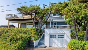 A coastal house with a wooden deck, a garage, and a staircase leading to the main entrance. - Gorgeous dog-friendly home with spectacular ocean views & deck - walk to Main St (Manzanita)