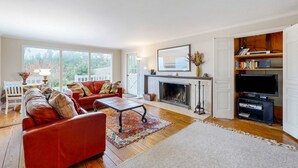 A living room with a fireplace, a television, and a bookshelf. - Oceanfront charmer with wood fireplace, games, & scenic deck - dog-friendly (Ocean Park)