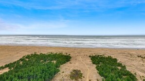A beach with a clear sky, sandy terrain, and green vegetation. - Oceanfront charmer with wood fireplace, games, & scenic deck - dog-friendly (Ocean Park)