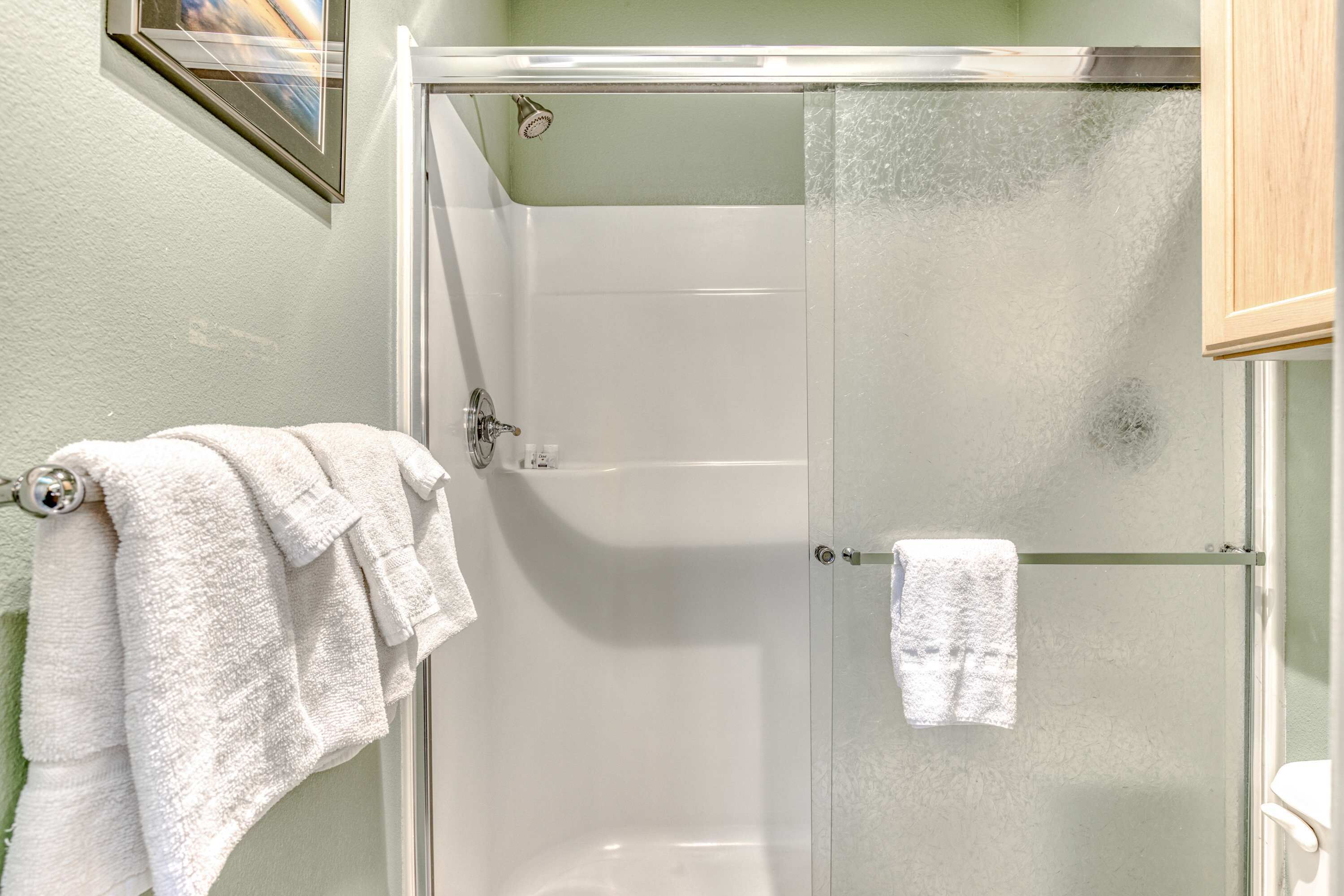 A glass-enclosed shower stall with a white towel hanging on the door handle.