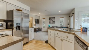 A modern kitchen with stainless steel appliances, a dishwasher, and a dining area with a sofa and table.