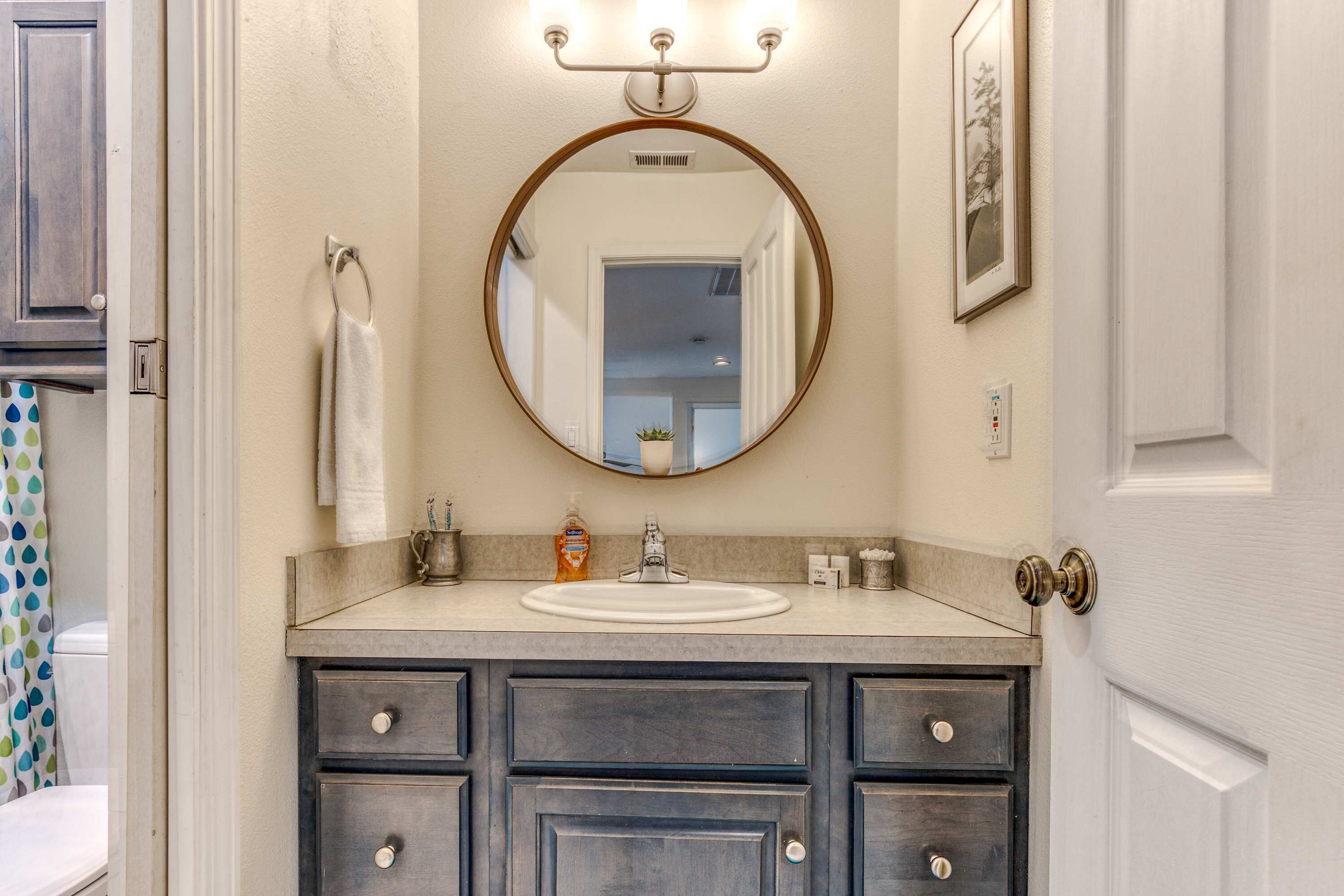 A bathroom with a round mirror, a sink, and a cabinet with drawers.