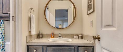 A bathroom with a round mirror, a sink, and a cabinet with drawers.
