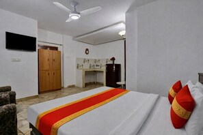 Ein Hotelzimmer mit Bett, Deckenventilator, Fernseher, Schreibtisch und Kleiderschrank.