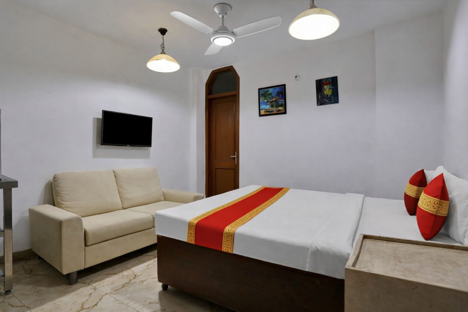 A bedroom with a bed, a sofa, a TV, and a ceiling fan.
