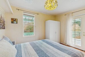 Une chambre à coucher avec un grand lit, une armoire, une fenêtre donnant sur un beau paysage et un luminaire suspendu.