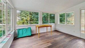 A room with large windows, a wooden table, and a radiator. - Charming home on the Siuslaw River with a fire pit, WiFi,  & W&D (Mapleton)