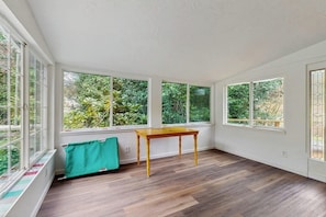 A room with large windows, a wooden table, and a radiator. - Charming home on the Siuslaw River with a fire pit, WiFi,  & W&D (Mapleton)