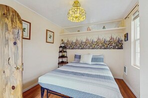 Ein Schlafzimmer mit einem Bett, einer Chandelieber, einer Wanddekoration mit Blumenmuster und einer Holztür.