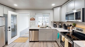 A modern kitchen with stainless steel appliances, a dishwasher, and a microwave. - Cozy condo with sun room, washer & dryer, close to the river (Florence)