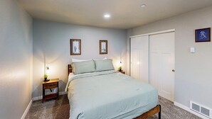 A bedroom with a bed, nightstands, a dresser, a door, and framed pictures on the wall. - Cozy condo with sun room, washer & dryer, close to the river (Florence)