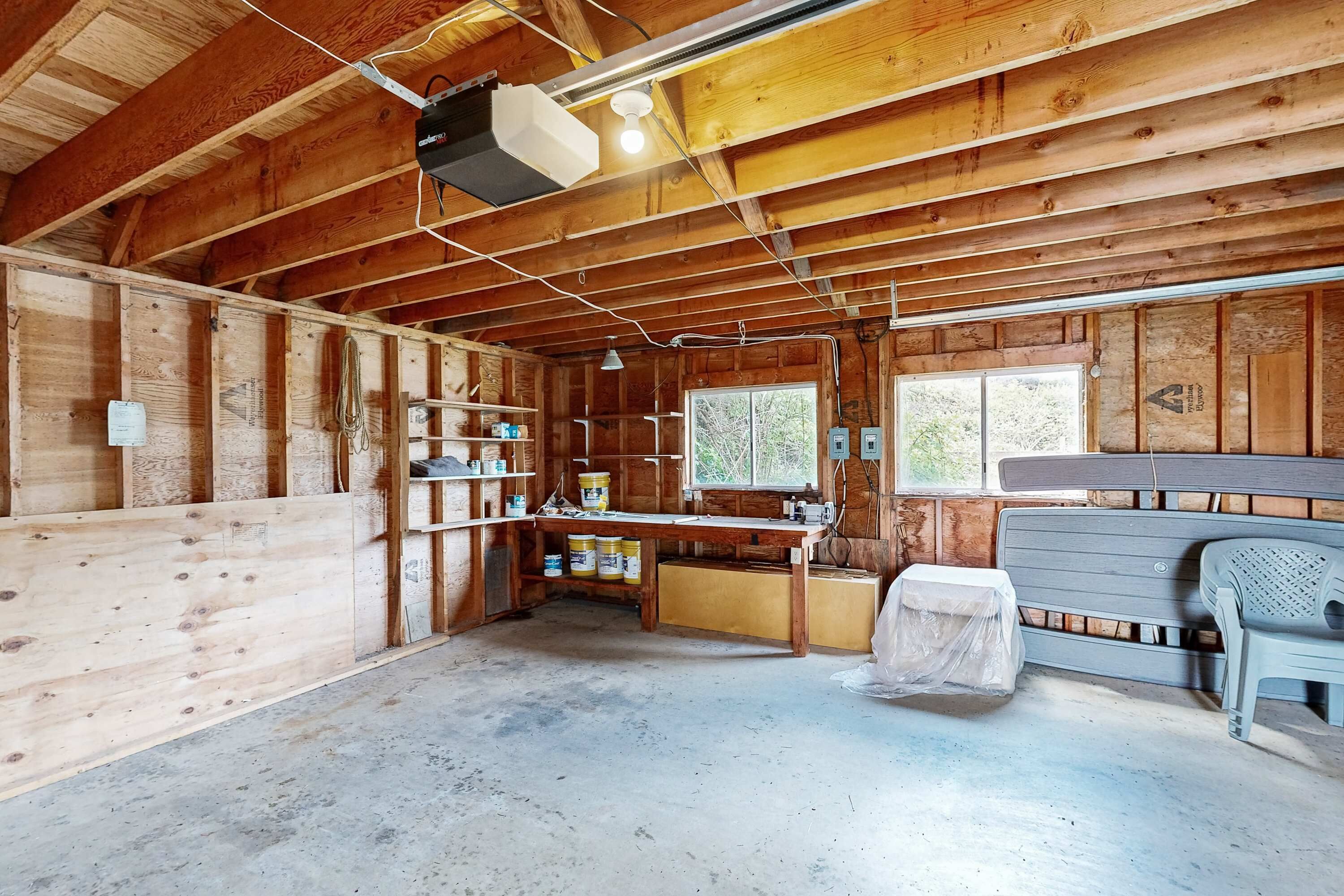 A wooden cabin interior with a kitchen area, a window, and a ceiling fan.