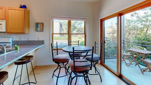 Una cocina moderna con encimera de granito, armarios de madera y un comedor con una mesa redonda y cuatro sillas.