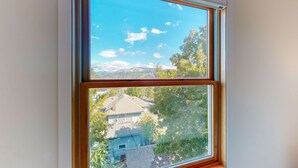 Una ventana con vista a una casa y árboles.