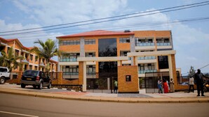 Un edificio de varios pisos con tejado rojo, ventanas amplias y una entrada porticada.