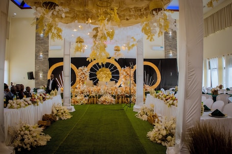 An indoor event space with a stage, floral arrangements, and a green carpet.. Centre Saint Vincent Pallotti