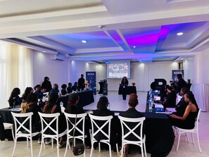 A conference room with a stage, white chairs, and a presentation screen. - Centre Saint Vincent Pallotti (Kigali)
