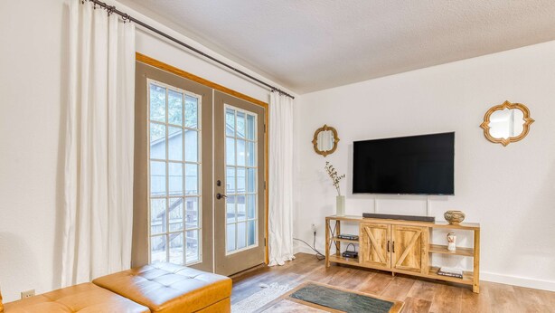 Una sala de estar con sofá, mesa de centro, televisor, aparador de madera y puerta corrediza de vidrio.