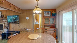 Ruokailutila, jossa on puinen pöytä, tuolit, televisio ja koristeellinen kattovalaisin.