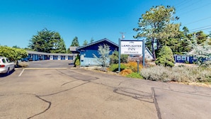 A motel with a blue exterior, a sign indicating the entrance, and a parking lot. - Retro-chic room near beach with fast WiFI - walk to downtown shops & eateries (Bandon)