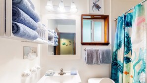 A bathroom with a white sink, a toilet, a mirror, and a shower curtain with a sea turtle design. - Retro-chic room near beach with fast WiFI - walk to downtown shops & eateries (Bandon)